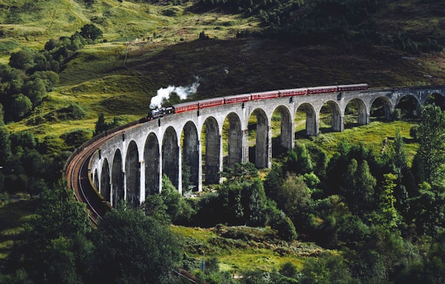 Image of a train rounding a curved, stone bridge